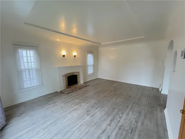 an empty room with wooden floor and fireplace