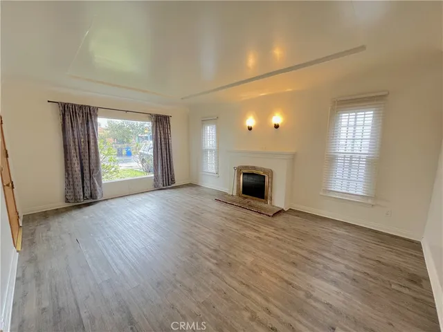 an empty room with windows fireplace and wooden floor