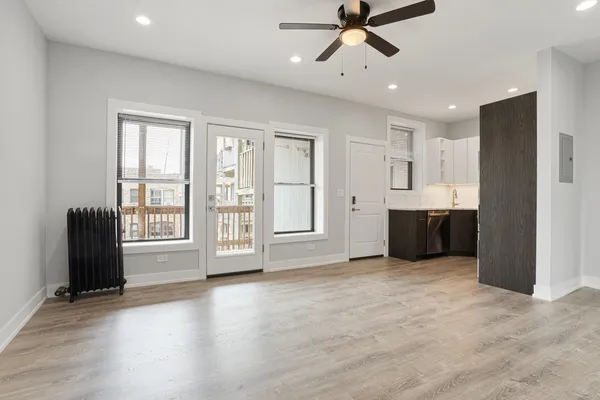 a view of an empty room with a window and wooden floor
