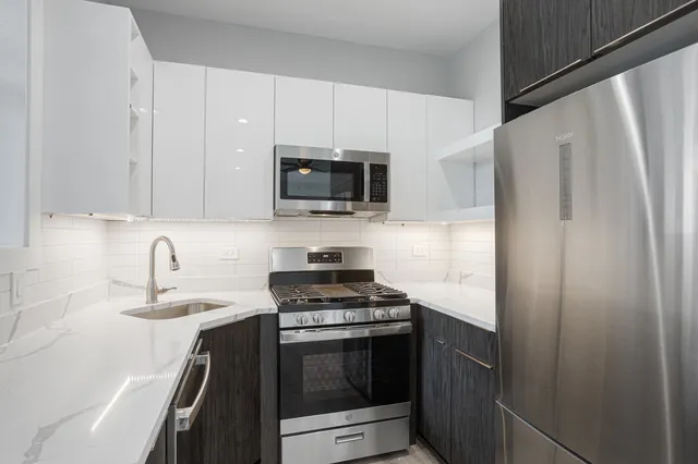 a kitchen with refrigerator a microwave a sink and cabinets