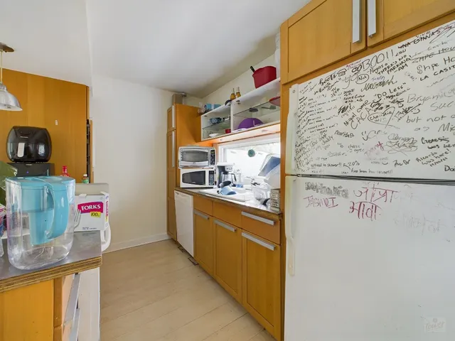 a view of a kitchen with fridge and wooden floor