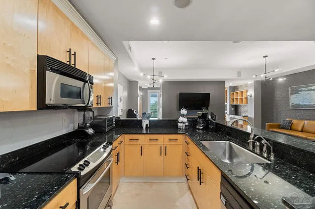 a large kitchen with granite countertop a large counter top space a sink stainless steel appliances and cabinets