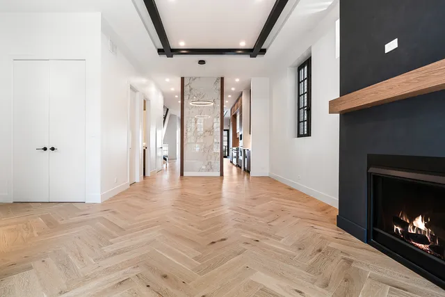 a view of an empty room with wooden floor and a fireplace