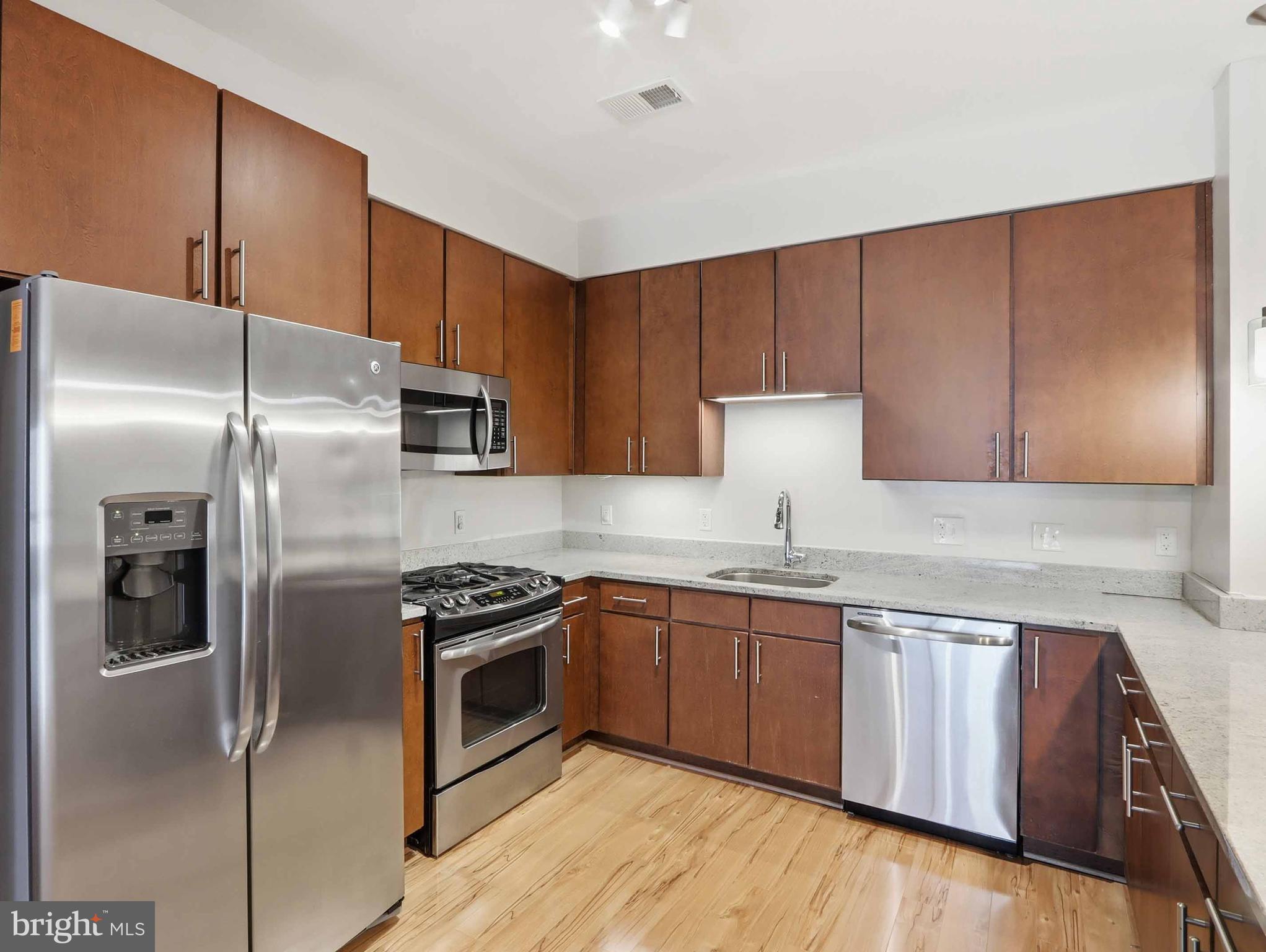 8005 13th Street, Unit 411 Silver Spring, MD 20910 - Photo 24 of 33 a kitchen with stainless steel appliances granite countertop a refrigerator a sink and white cabinets