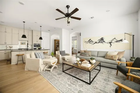 a living room with furniture kitchen view and a chandelier