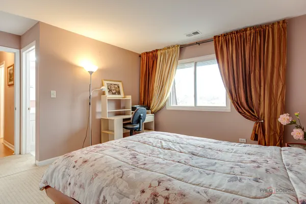 a bedroom with a bed and a large mirror next to a window