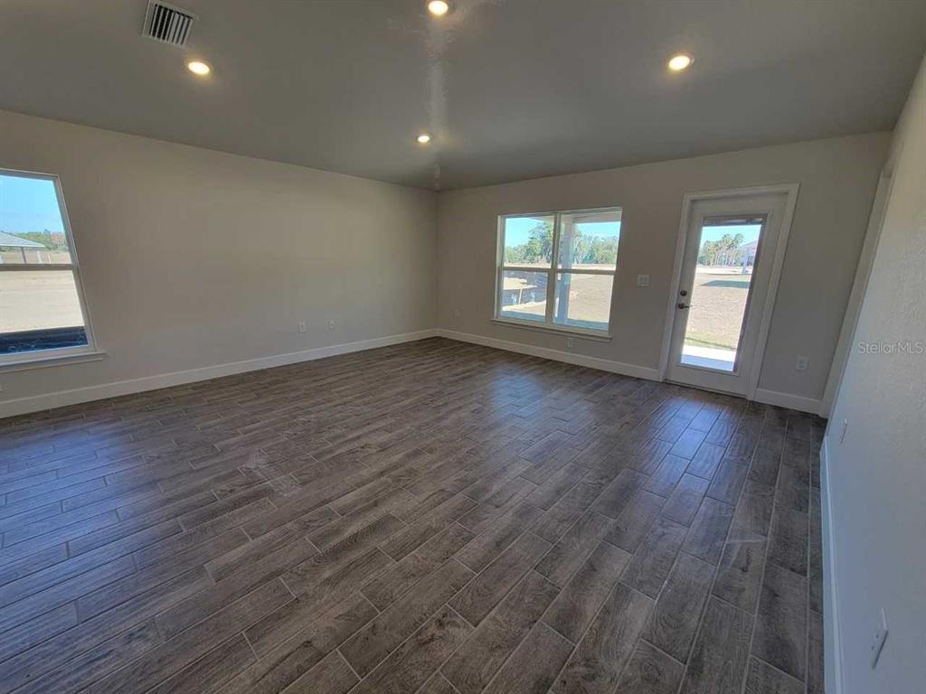 4513 Southwest 91st Ln Road Ocala, FL 34476 - Photo 11 of 36 an empty room with wooden floor and windows