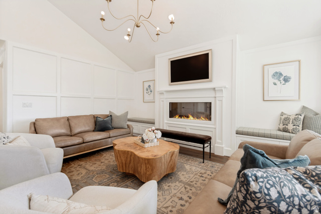 1567 Ridgeview Circle Farmington, UT 84025 - Photo 14 of 55 Sophisticated living room showcasing a linear gas fireplace with integrated shelving, vaulted ceiling with modern pendant lighting, plush seating arrangements, and a natural wood-finish accent table