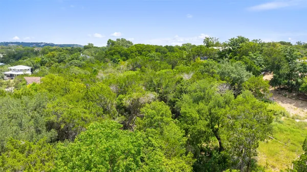 an aerial view of residential houses with outdoor space and trees all around