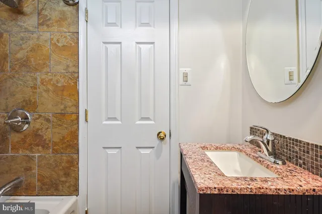 a bathroom with a granite countertop sink a mirror and shower