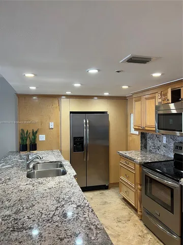 a large kitchen with stainless steel appliances kitchen island granite countertop a large counter top and oven
