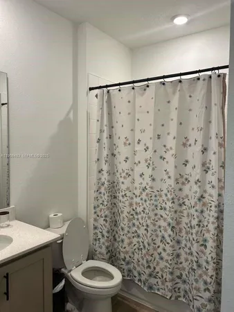 a white toilet sitting next to a shower curtain