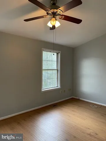 a view of an empty room with a window and a chandelier fan