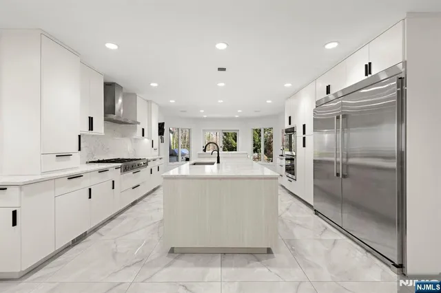 a large white kitchen with cabinets a sink dishwasher a stove and a refrigerator with wooden floor