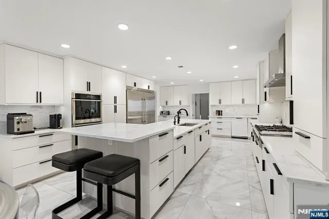 a large kitchen with stainless steel appliances granite countertop a lot of white cabinets and sink
