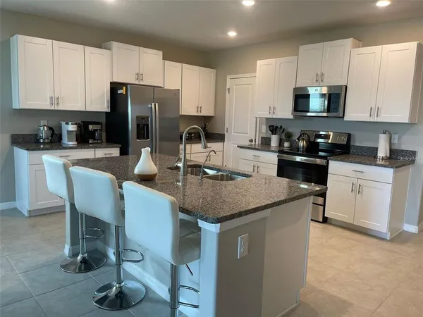 a kitchen with stainless steel appliances granite countertop a sink a stove a refrigerator a microwave and cabinets