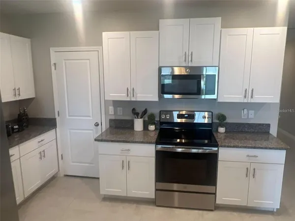 a kitchen with white cabinets and black appliances