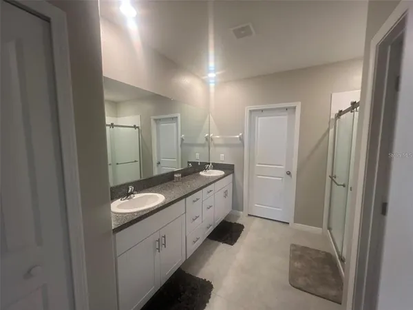 a spacious bathroom with a granite countertop sink a toilet a mirror and shower