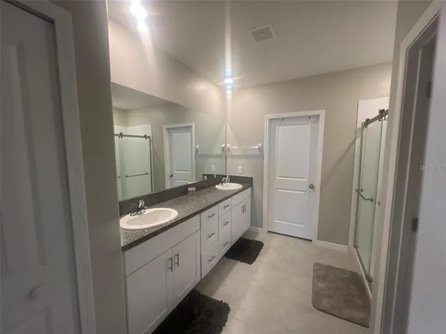 a spacious bathroom with a granite countertop sink a toilet a mirror and shower