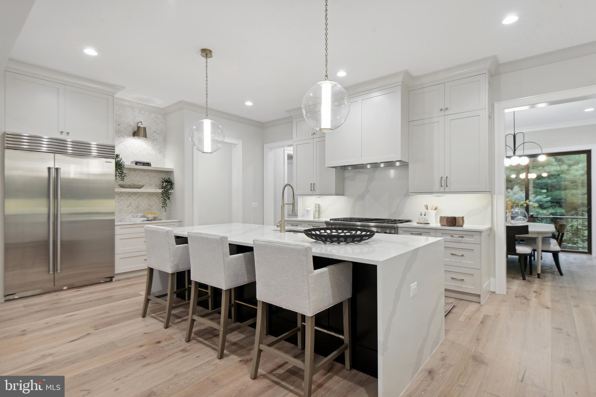 6523 Old Chesterbrook Road McLean, VA 22101 - Photo 4 of 17 a kitchen with stainless steel appliances granite countertop a stove a refrigerator a kitchen island a sink and white cabinets with wooden floor