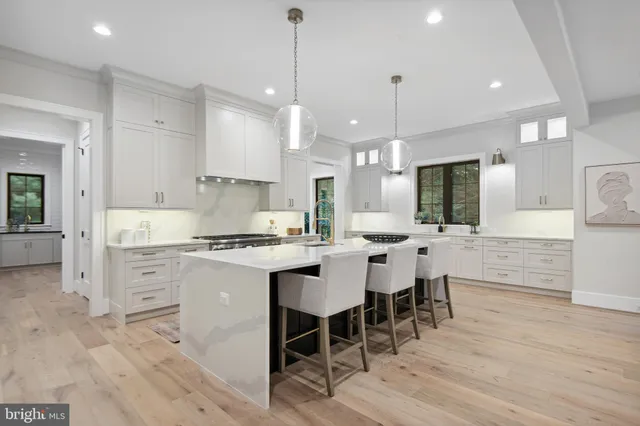 a kitchen with stainless steel appliances kitchen island granite countertop a dining table chairs and white cabinets