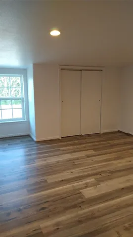 an empty room with wooden floor and windows with curtains
