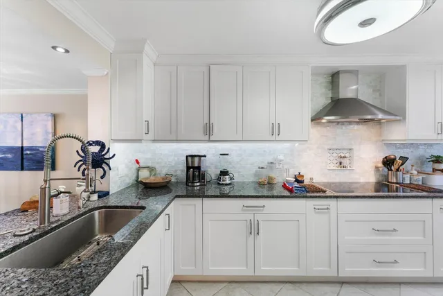 a kitchen with granite countertop a sink a stove and cabinets