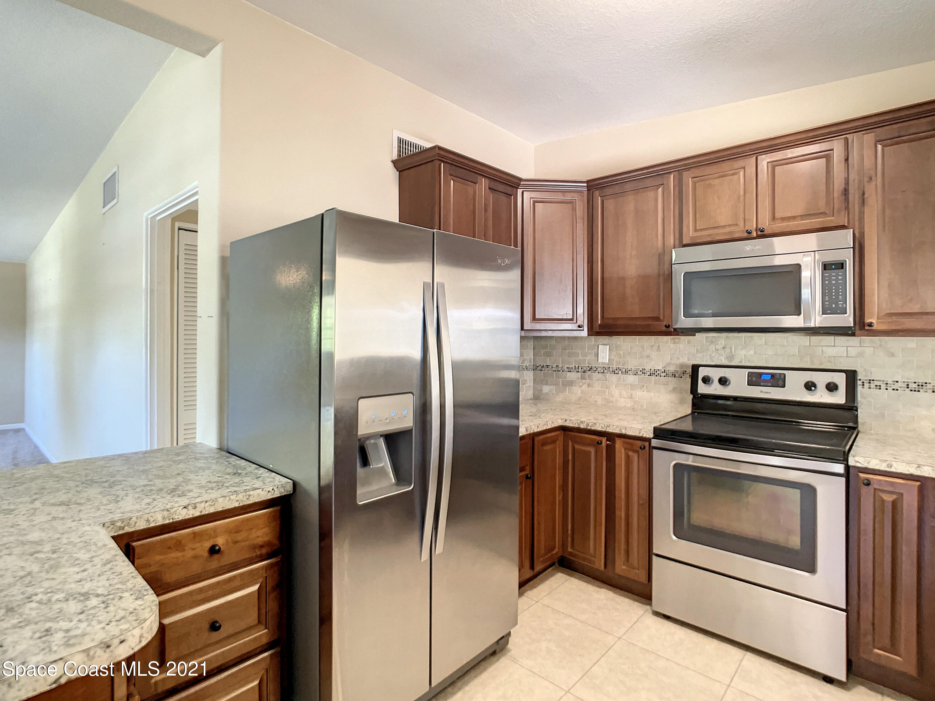 946 Santa Cruz Road Cocoa Beach, FL 32931 - Photo 5 of 26 a kitchen with granite countertop a refrigerator stove and microwave
