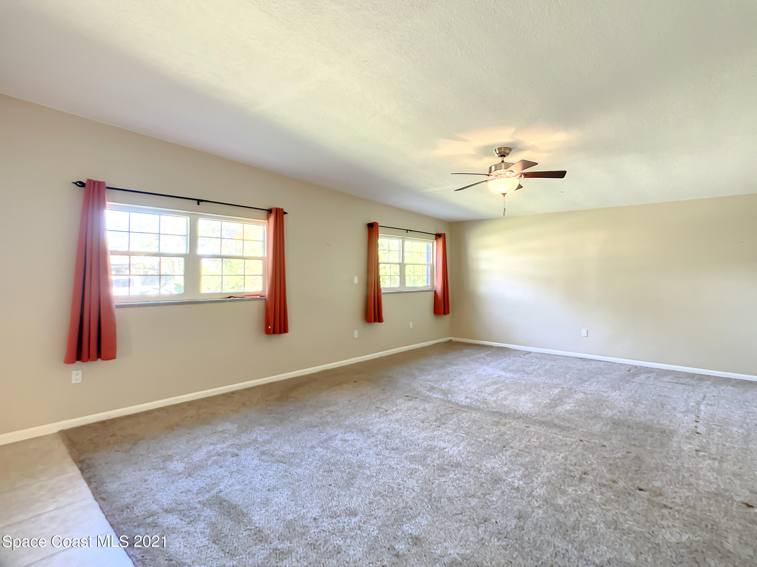 946 Santa Cruz Road Cocoa Beach, FL 32931 - Photo 7 of 26 an empty room with windows and chandelier fan