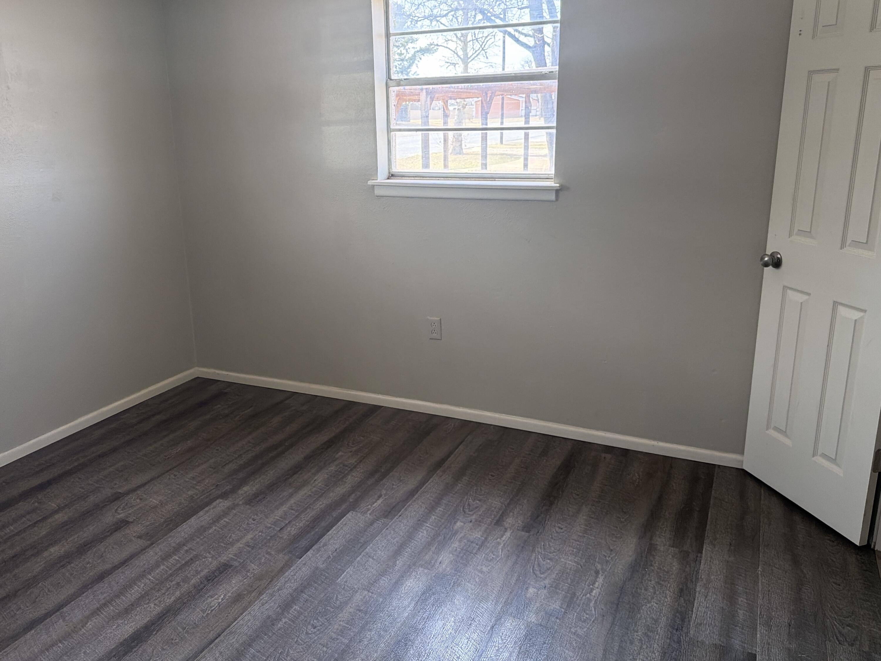 307 East 5th Street Sundown, TX 79372 - Photo 5 of 14 an empty room with wooden floor and windows