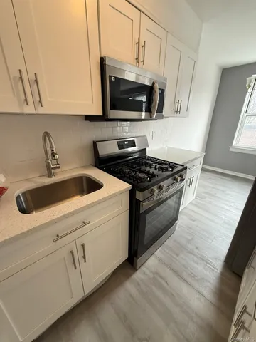 a kitchen with stainless steel appliances granite countertop a sink a stove a microwave and wooden cabinets