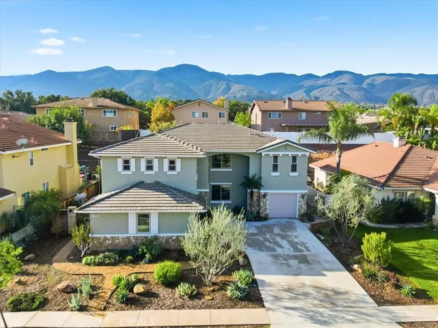 a front view of a house with a yard and mountain view in back