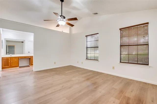 a view of an empty room with a window and wooden floor