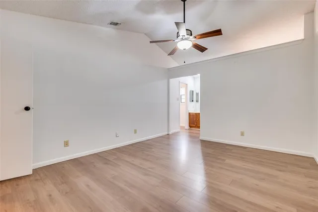 an empty room with wooden floor chandelier fan and windows