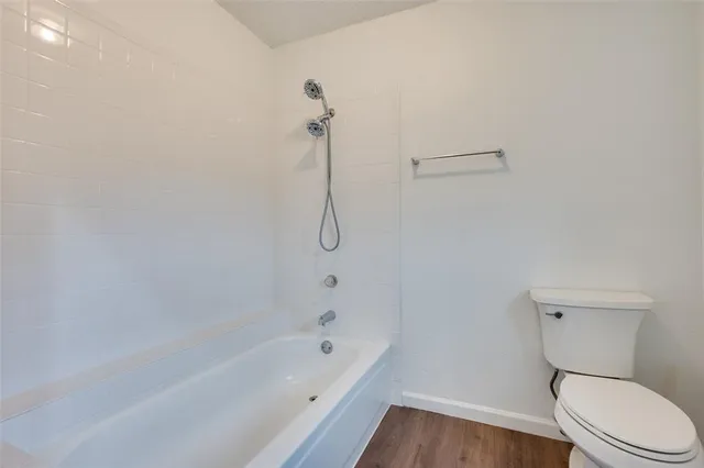 a white toilet sitting next to a bath tub