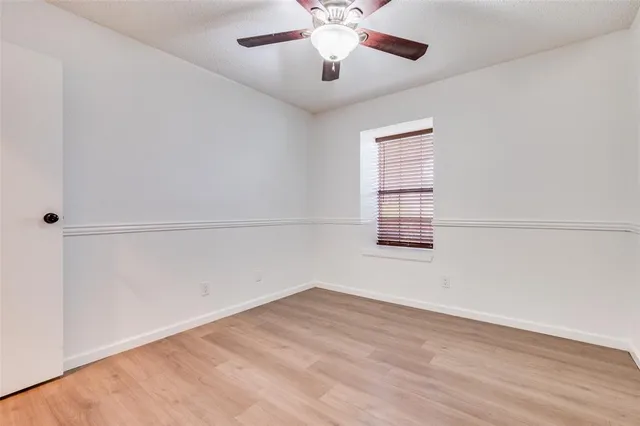 an empty room with chandelier fan and windows