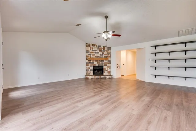 an empty room with wooden floor chandelier and windows