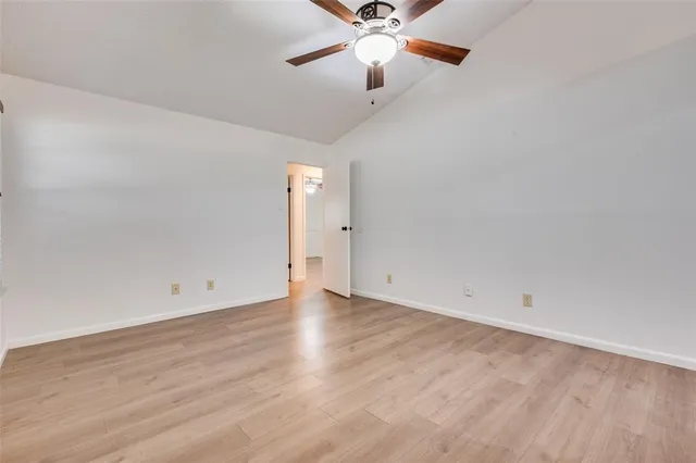 an empty room with wooden floor fan and windows