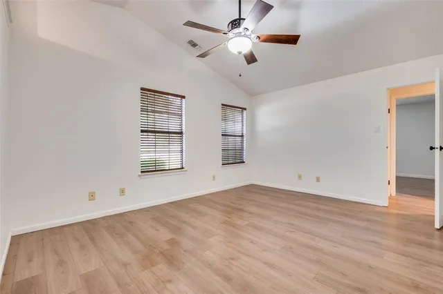 an empty room with chandelier fan and windows
