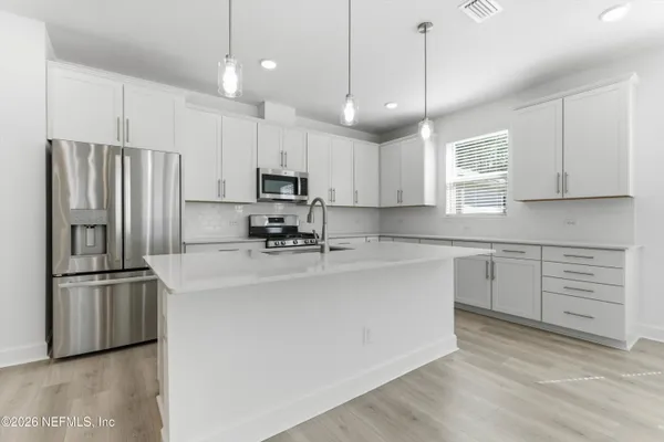 a kitchen with kitchen island a white cabinets and stainless steel appliances