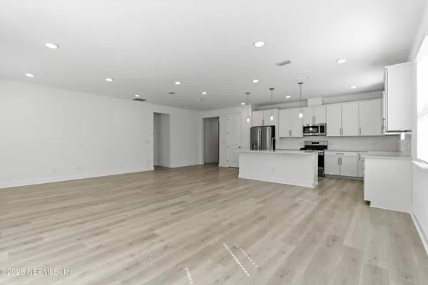 a view of a kitchen with kitchen island a sink wooden floor and white appliances