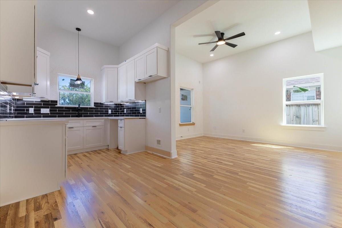 408 Armstrong Street, Unit B Houston, TX 77029 - Photo 2 of 14 a kitchen with granite countertop a stove a sink and white cabinets with wooden floor next to windows
