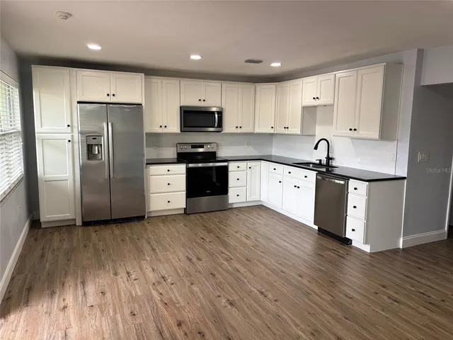 a kitchen with granite countertop stainless steel appliances a sink and refrigerator