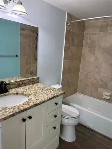 a bathroom with a granite countertop sink a toilet and bathtub