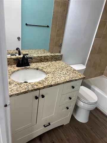 a bathroom with a granite countertop sink a toilet and a mirror