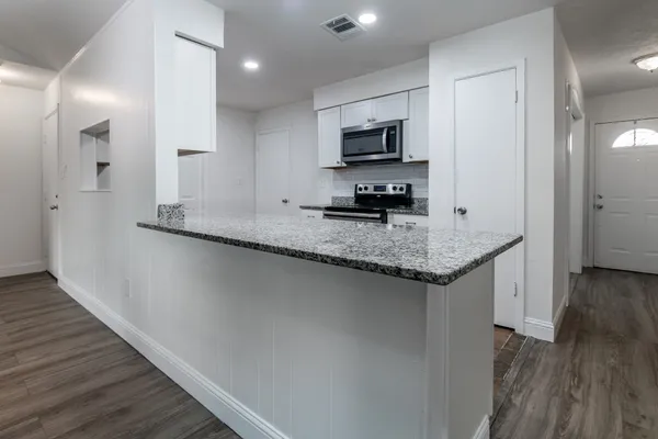a kitchen with granite countertop stainless steel appliances a sink stove top oven and wooden floor
