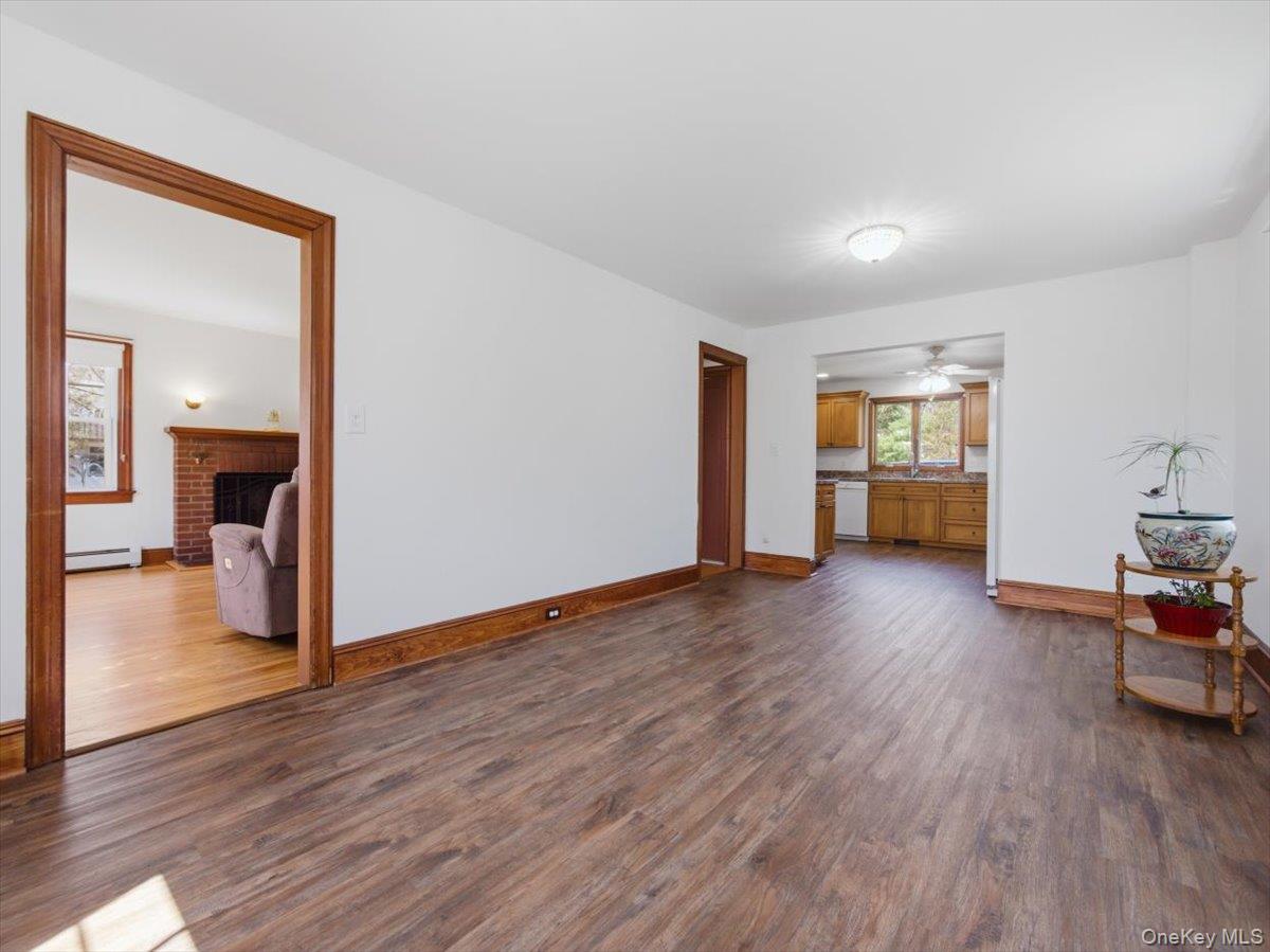 311 Gate Hill Coop Road Stony Point, NY 10980 - Photo 12 of 42 The Dining area features wood-look flooring and white walls, with a clear view into an additional room that has a brick fireplace