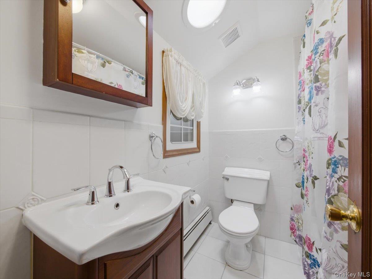 311 Gate Hill Coop Road Stony Point, NY 10980 - Photo 25 of 42 The bathroom features a vanity with a white sink and chrome faucet, a toilet, and white tiled walls