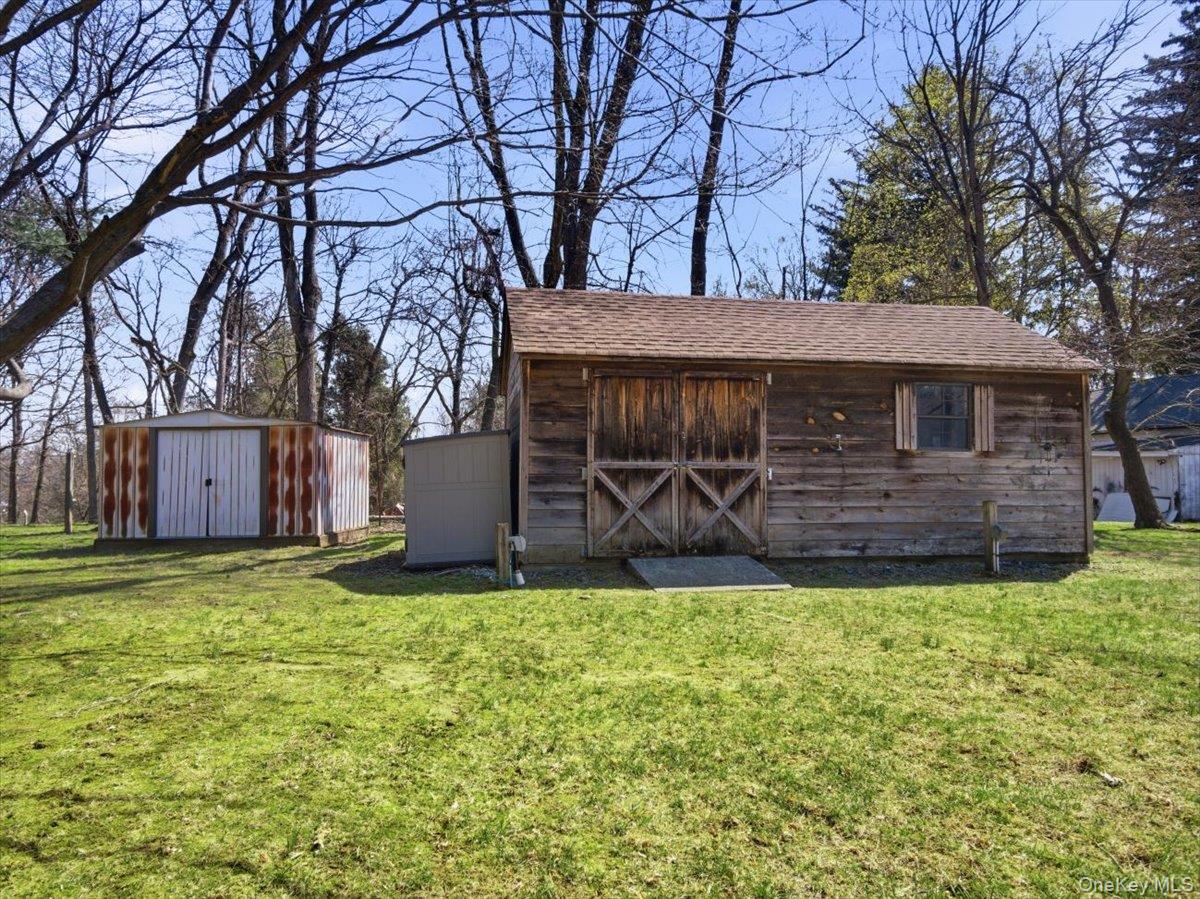 311 Gate Hill Coop Road Stony Point, NY 10980 - Photo 37 of 42 The property features a spacious yard with a wooden shed, an additional metal shed, and a smaller grey shed, all surrounded by mature trees