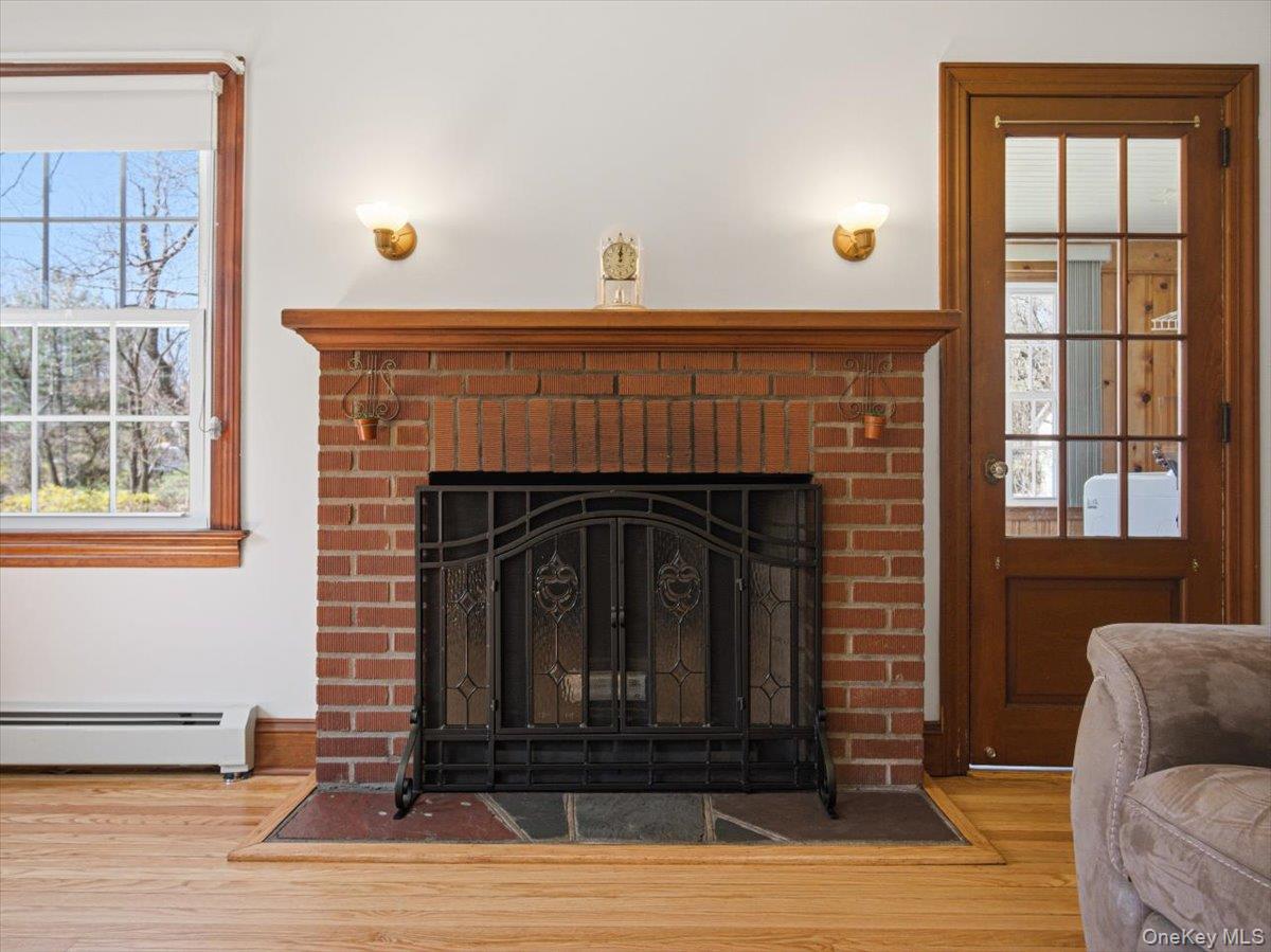 311 Gate Hill Coop Road Stony Point, NY 10980 - Photo 5 of 42 This interior view features a brick fireplace with a decorative metal screen, set against a white wall with two wall sconces